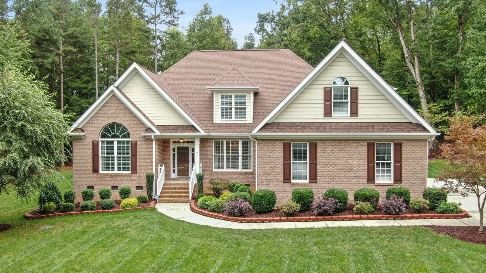 Brick home with an arched window and brown architectural shingle roof