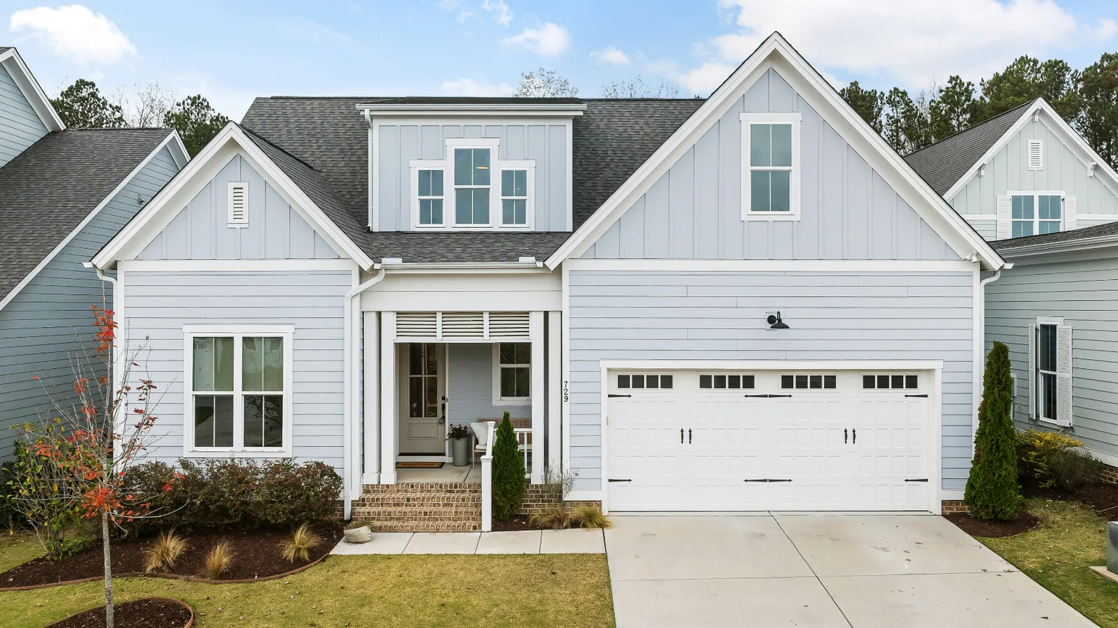 Light blue siding home with a white garage door and gray shingle roof