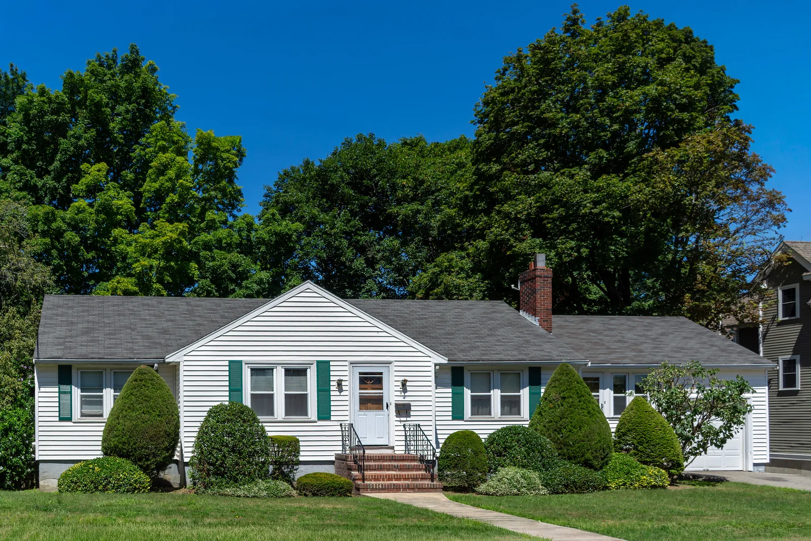 White house with dark asphalt shingle roof and brick chimney