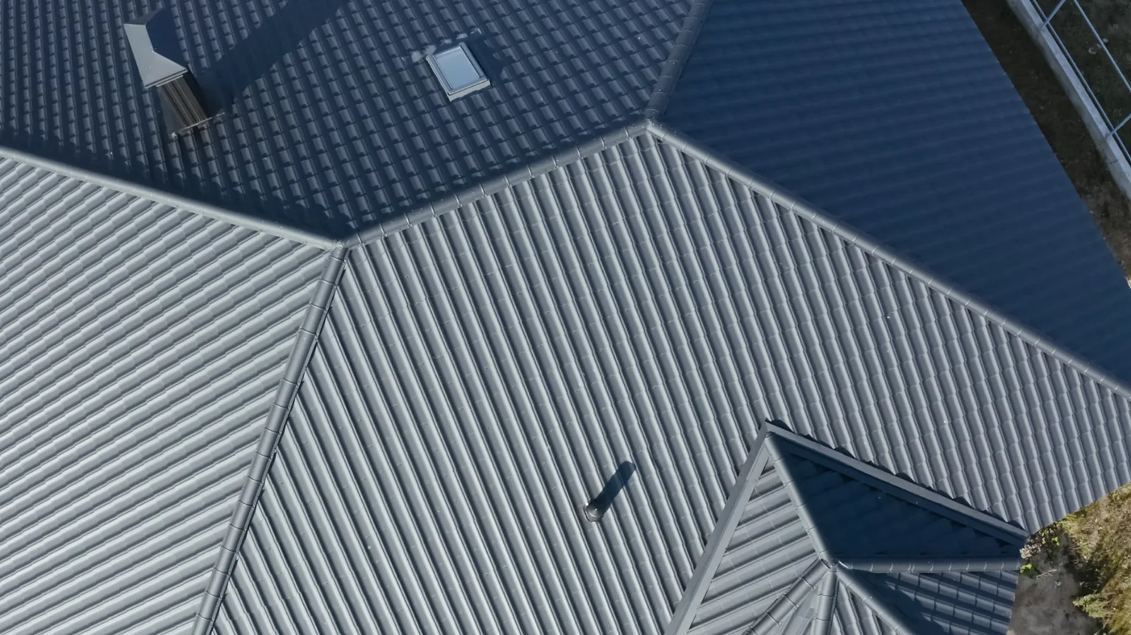Aerial view of gray metal roof sections with a skylight and chimney